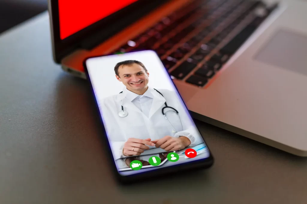 doctor on smartphone video call near laptop utc